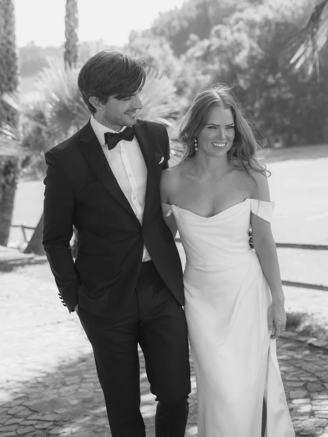Black-and-white portrait of a couple walking among palm trees