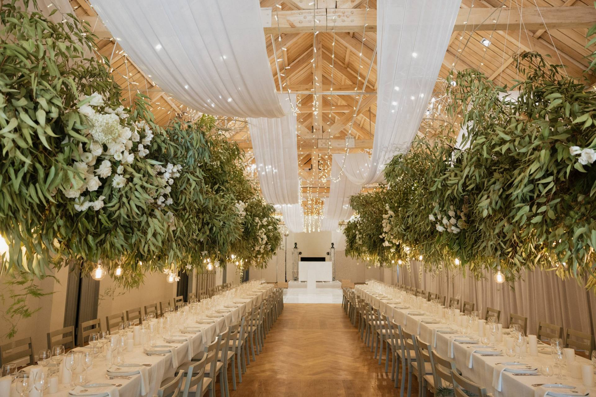 Elegant wedding reception hall with hanging greenery and draped ceiling