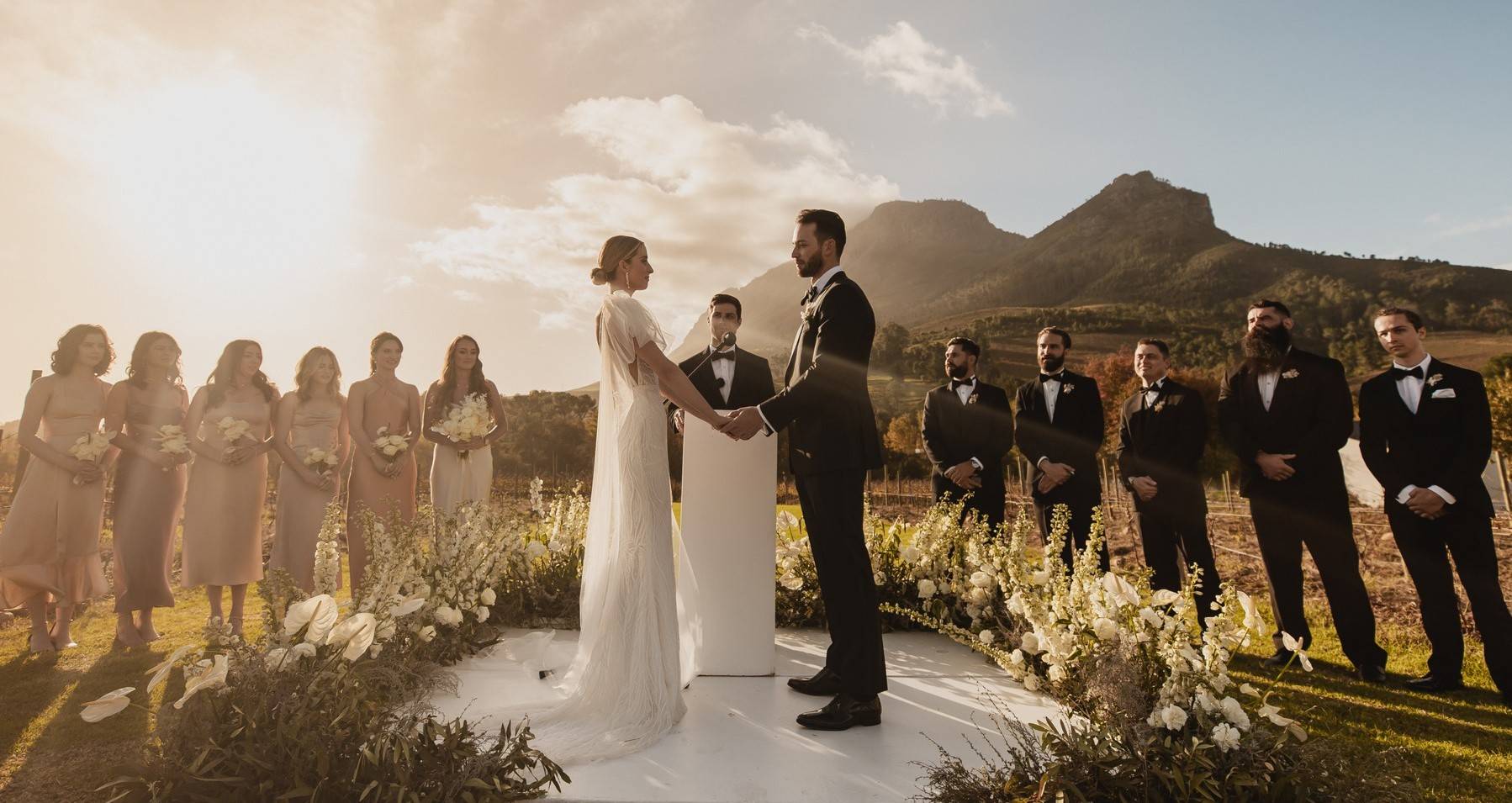 Outdoor wedding ceremony surrounded by white flowers with mountain scenery