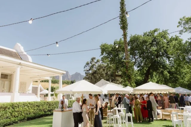 Outdoor cocktail reception with guests, fairy lights and umbrellas
