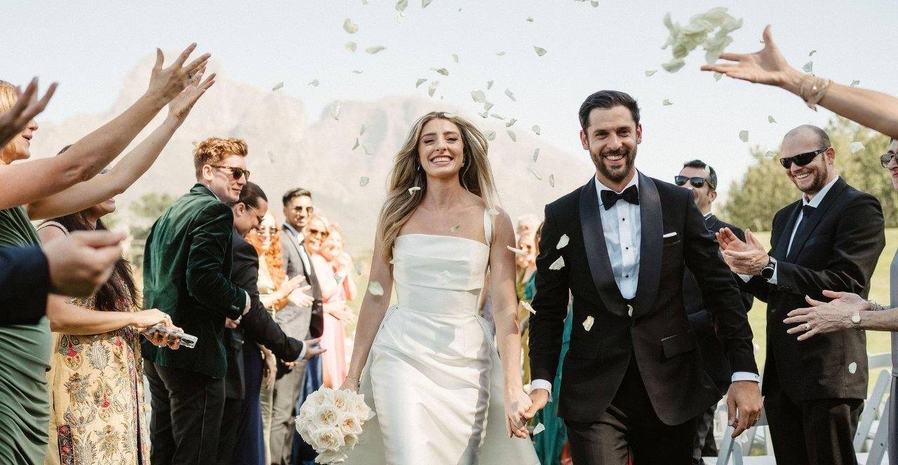 Bride and groom walking down the aisle as guests throw flower petals