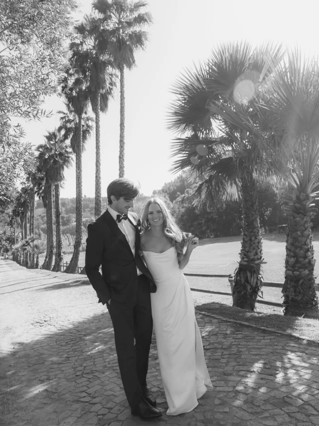Black-and-white photo of a couple on a palm-lined driveway