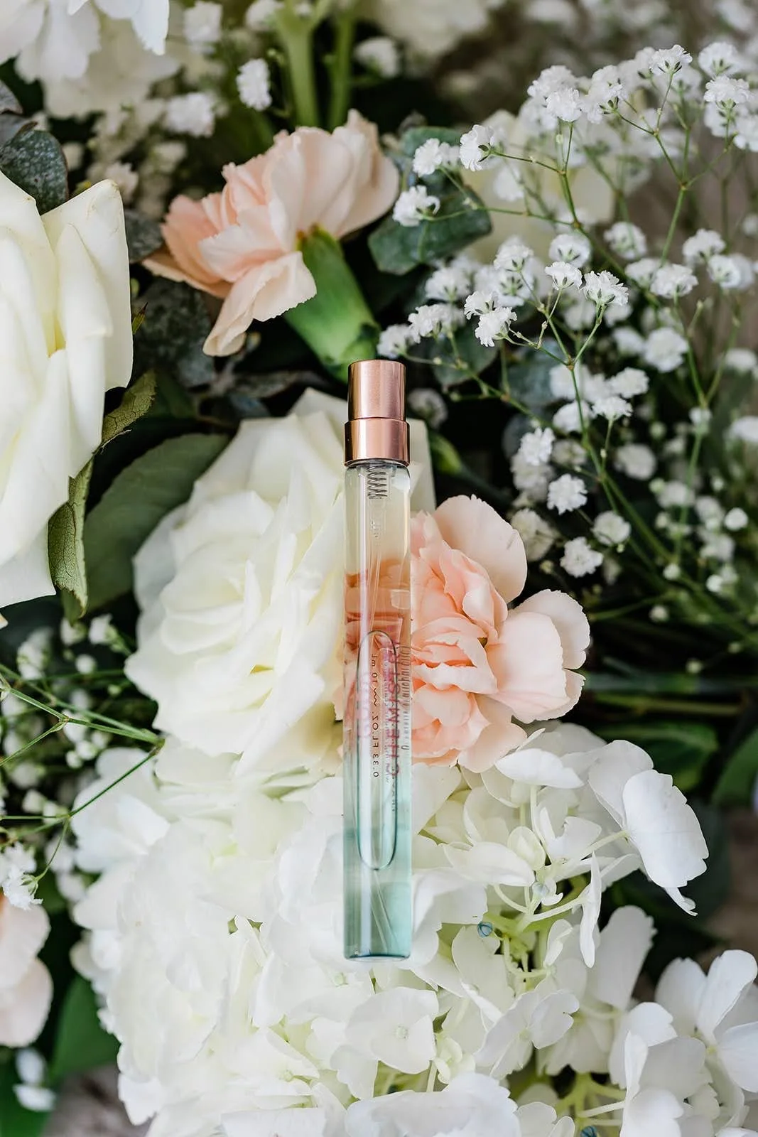 Perfume nestled in a white and blush bridal bouquet