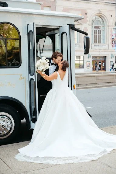 Bride and groom kissing at the door of a vintage white trolley