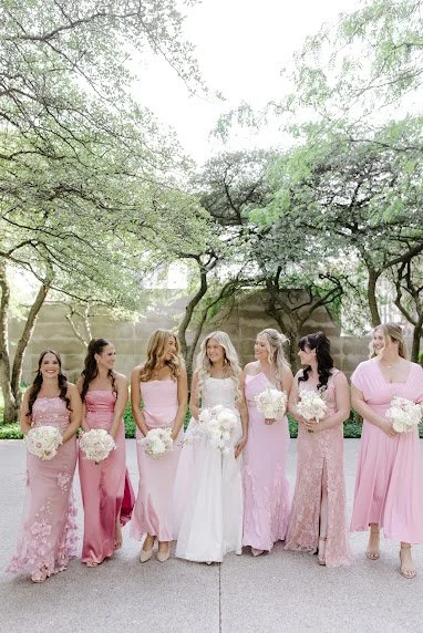 Bride with bridesmaids in shades of pink laughing outdoors in a Chicago park