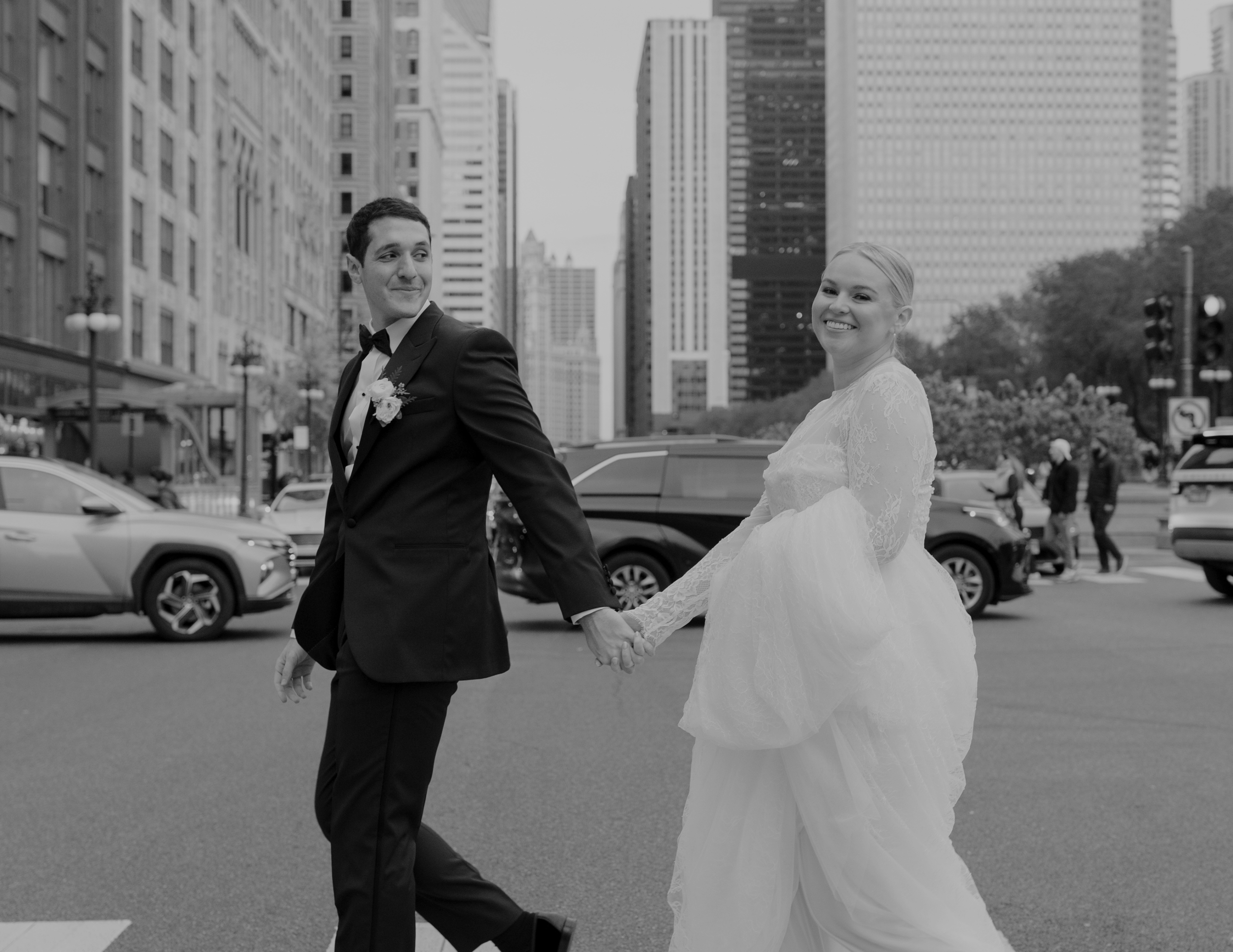 Bride and groom crossing a Chicago street, looking back and smiling