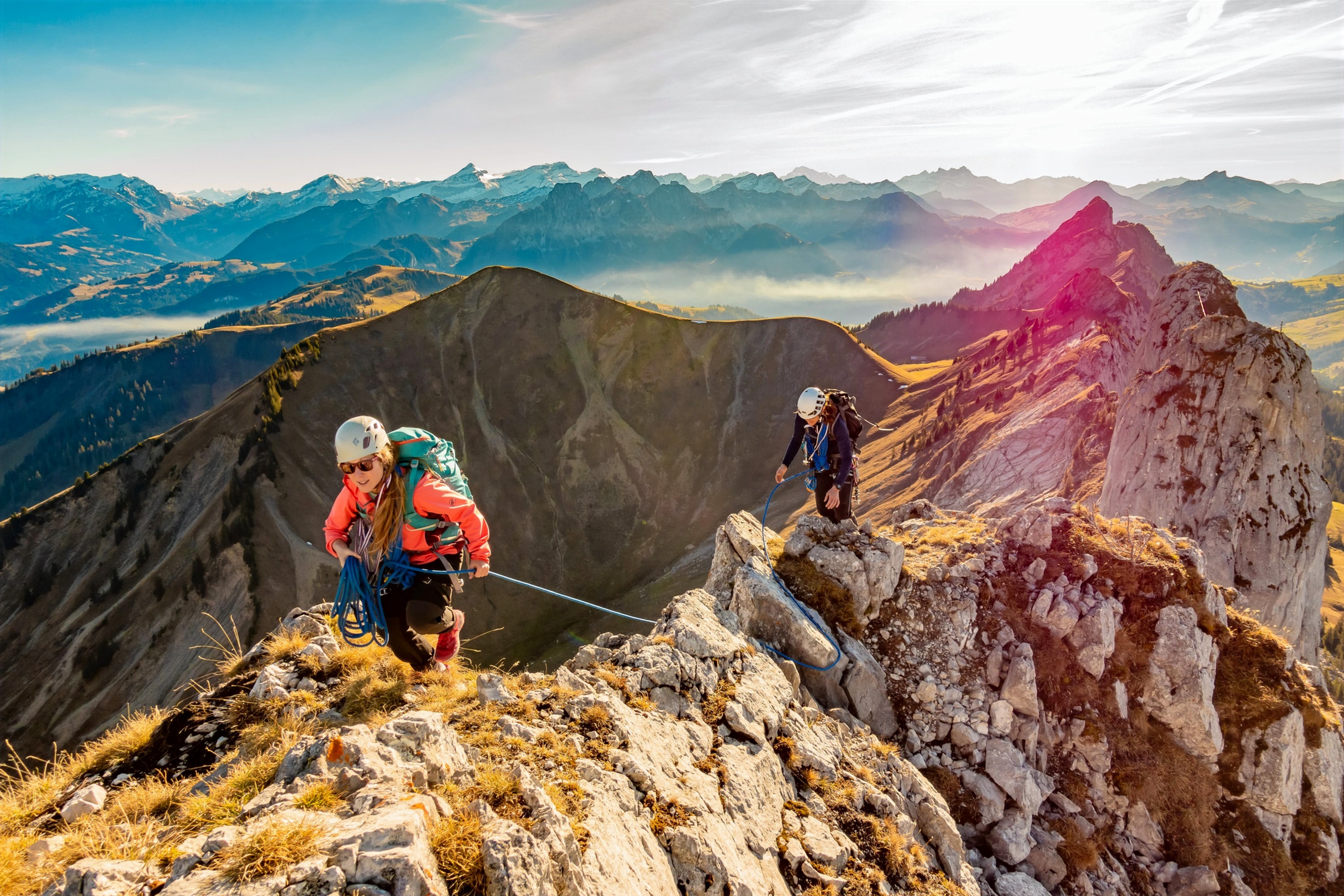 Two mountain climbers ascending an alpine ridge at sunrise