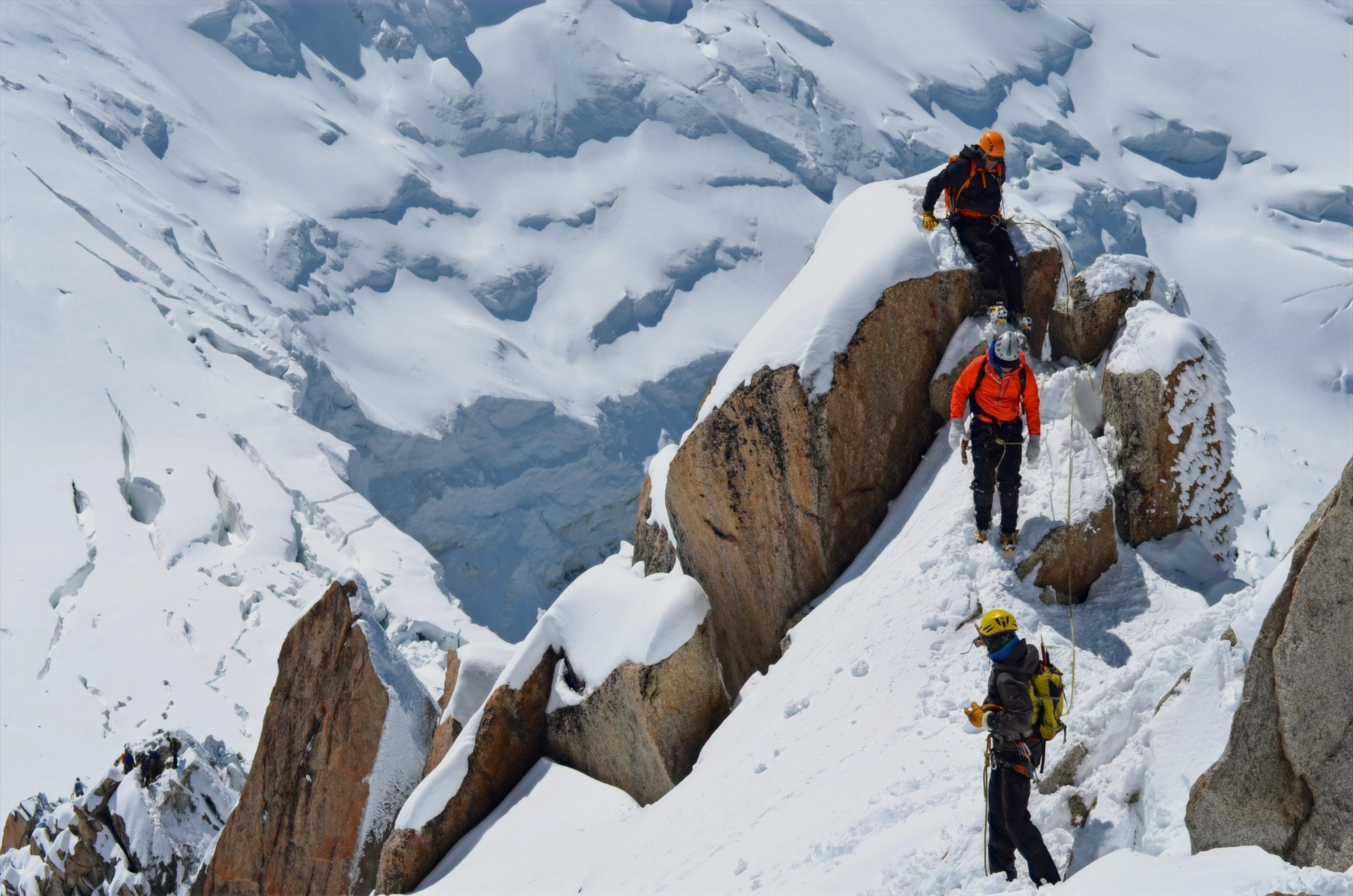 Three mountain climbers scaling a snow-covered peak