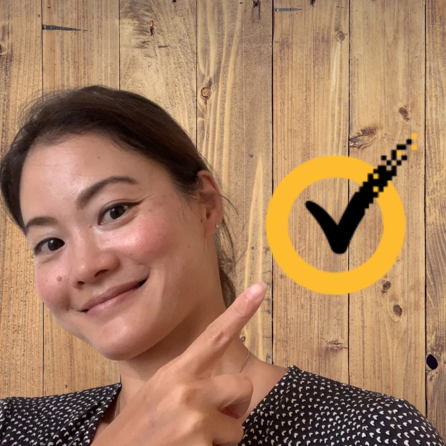 Woman pointing at a yellow checkmark logo at a branded photo booth