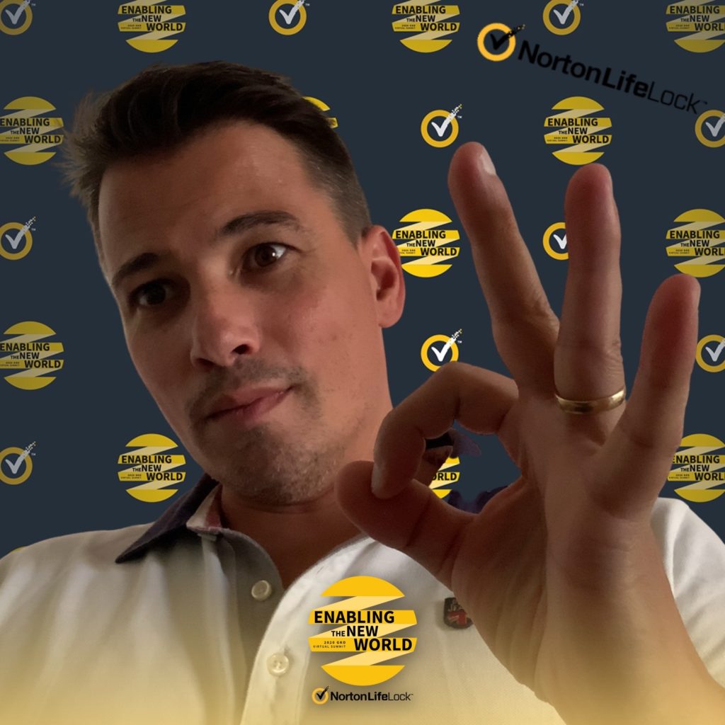 Man making an OK gesture at the NortonLifeLock event backdrop