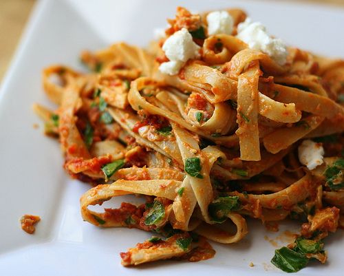 Plated fettuccine with tomato sauce, herbs and crumbled cheese