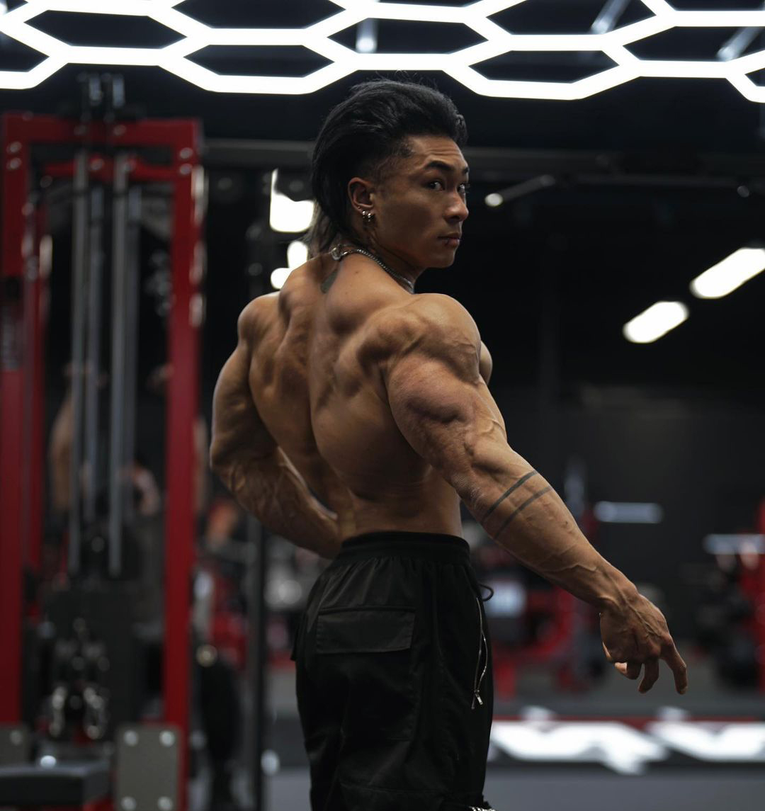 Athlete back muscles in red-lit gym
