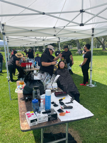 Hair styling service under a white tent at an outdoor community event