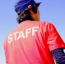 Person from behind wearing a red STAFF t-shirt and blue cap