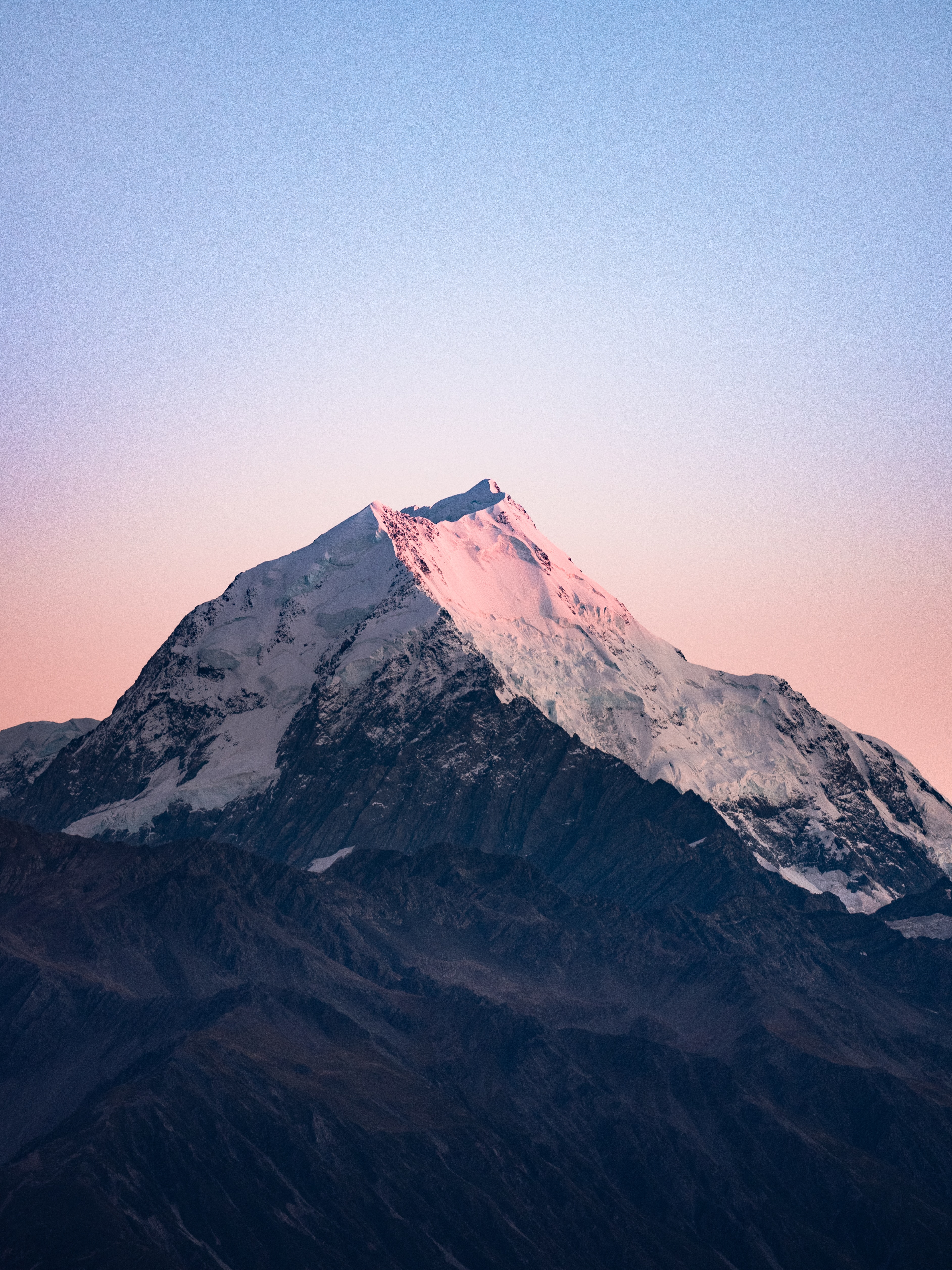 Snow-capped mountain peak at sunrise with pink and blue sky