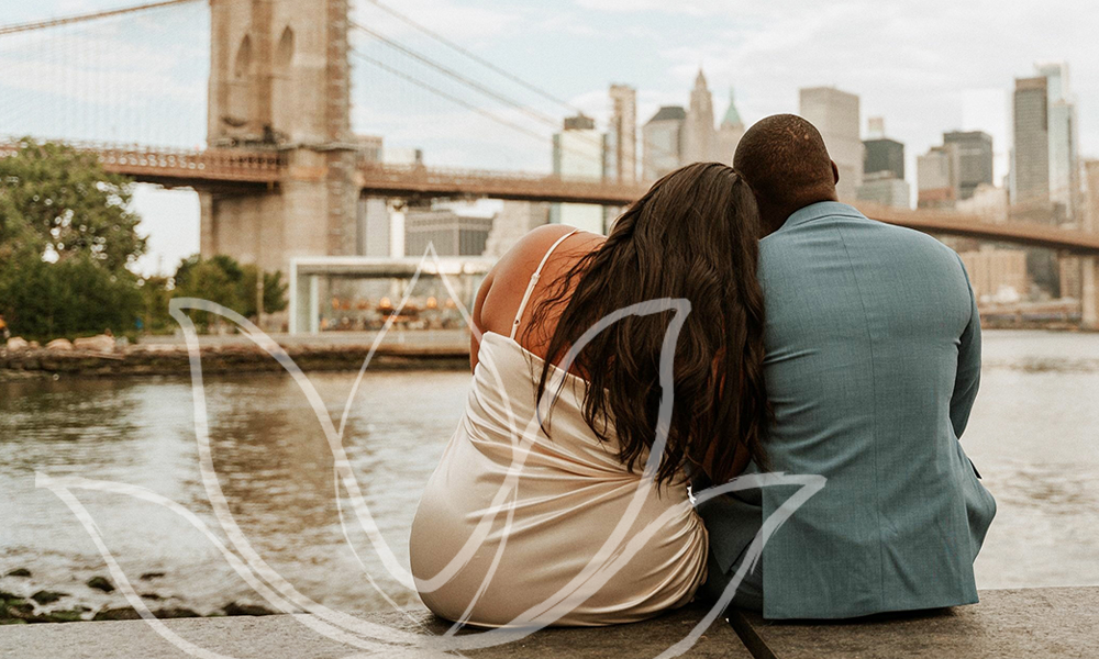 A couple sitting side by side facing the Brooklyn Bridge and NYC skyline
