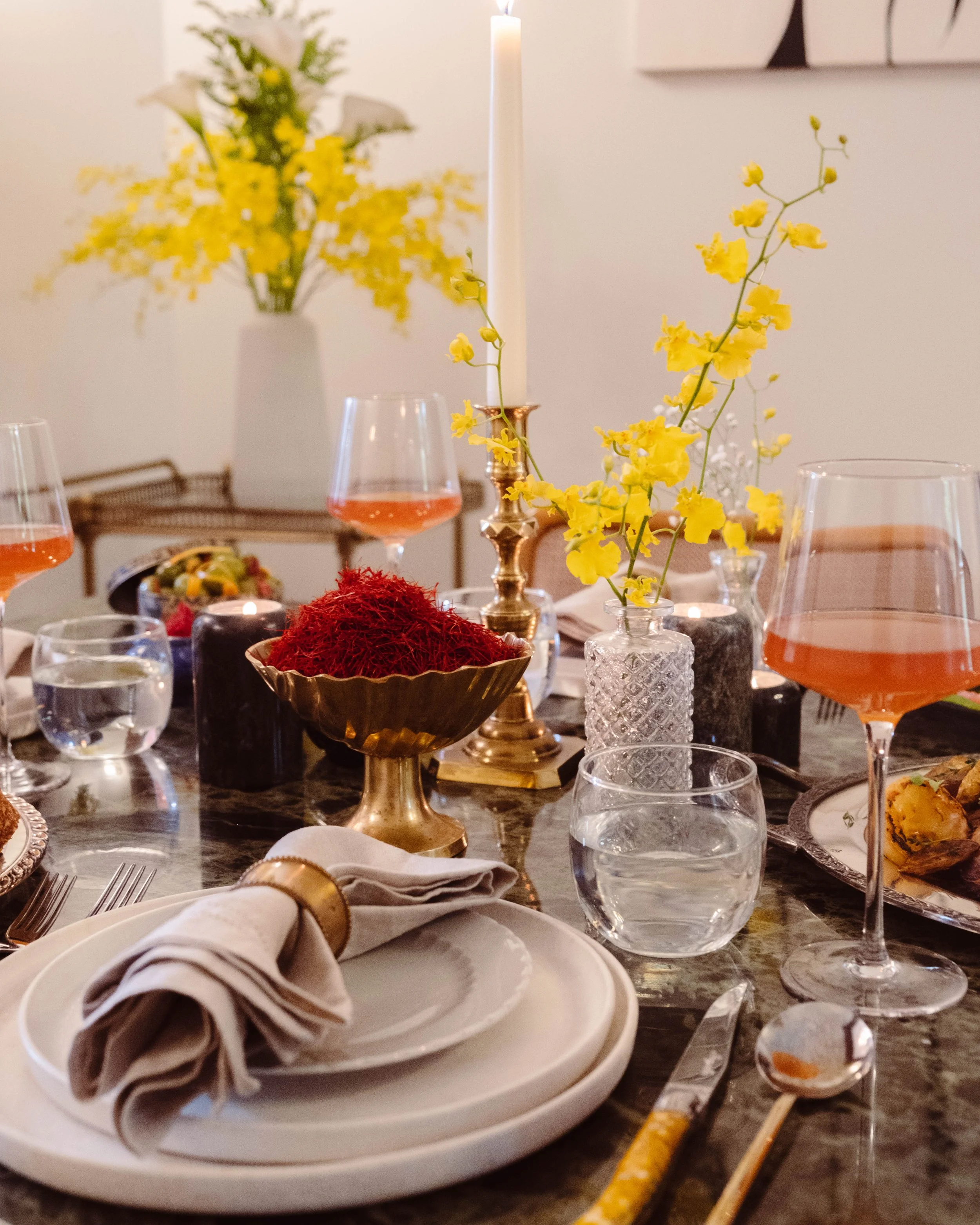 Elegant dinner table with yellow orchids, saffron in a gold bowl, brass candlestick and rosé