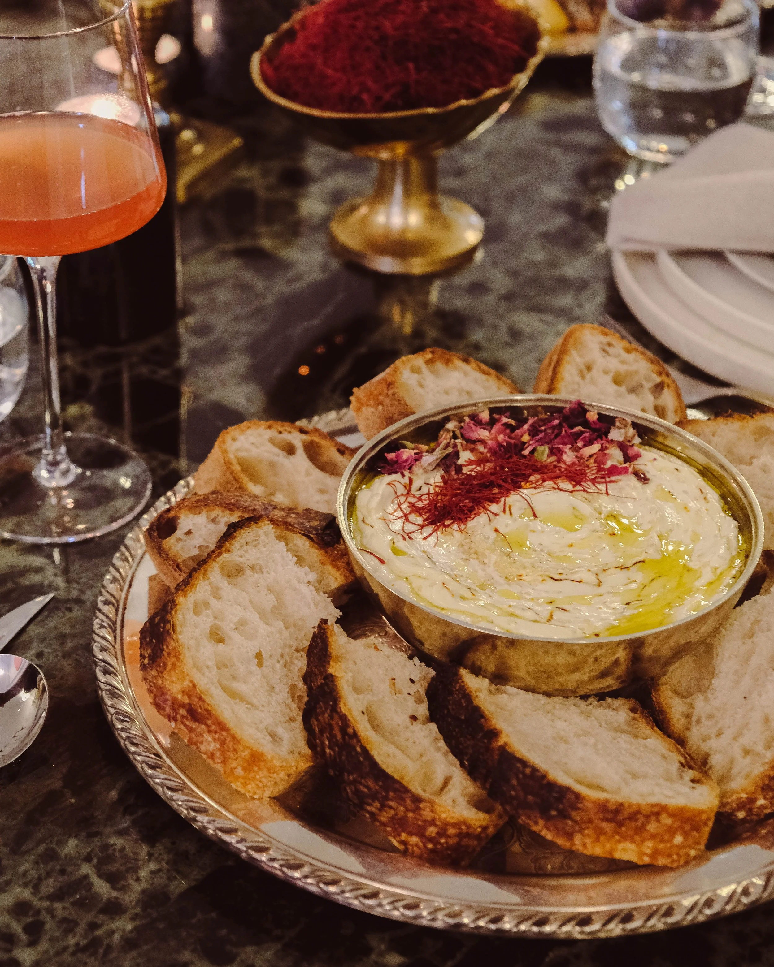 Silver tray of toasts surrounding labneh topped with saffron and rose petals