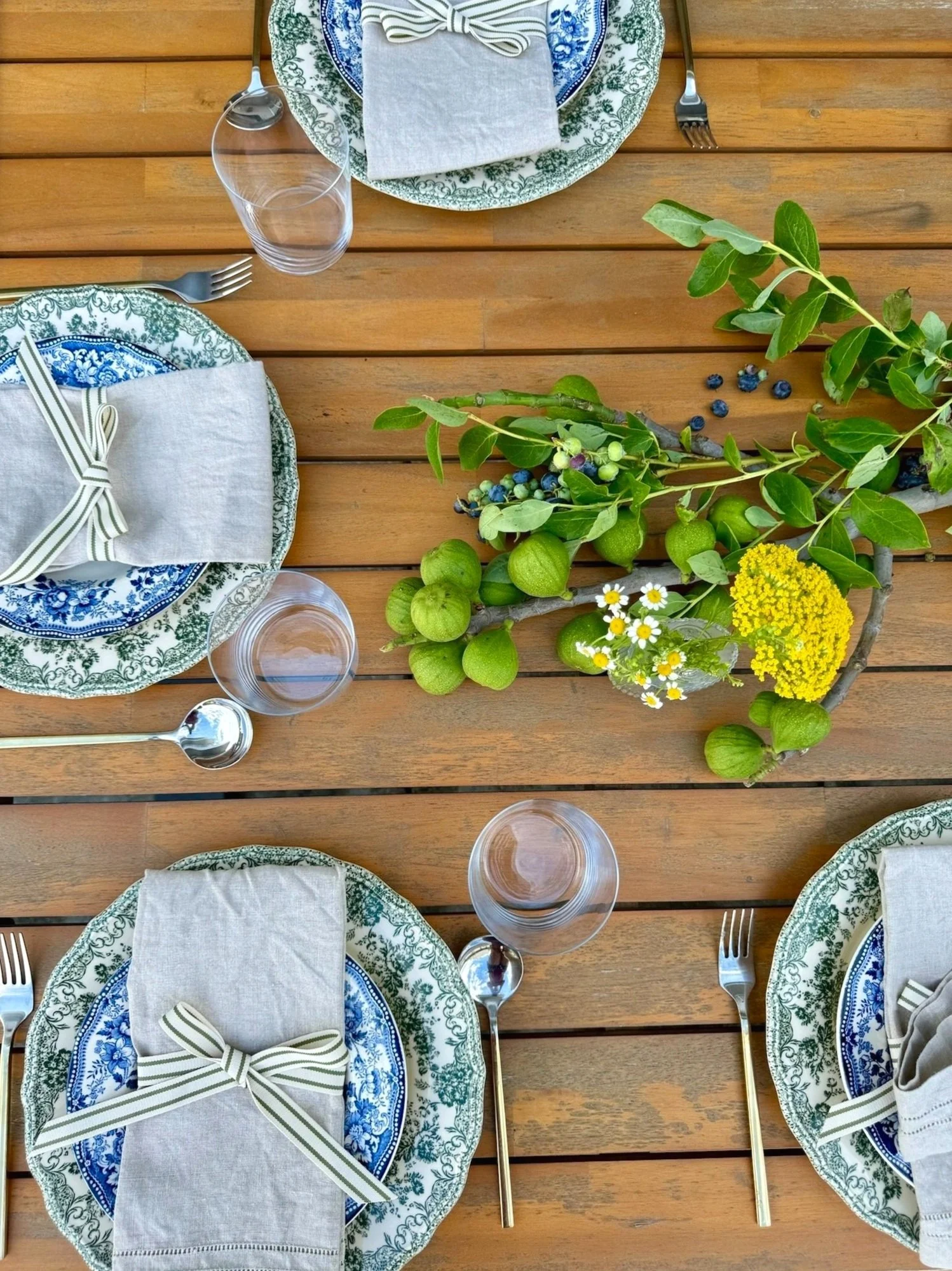 Overhead outdoor table with blue-green toile plates, ribbon-tied napkins and a botanical centerpiece