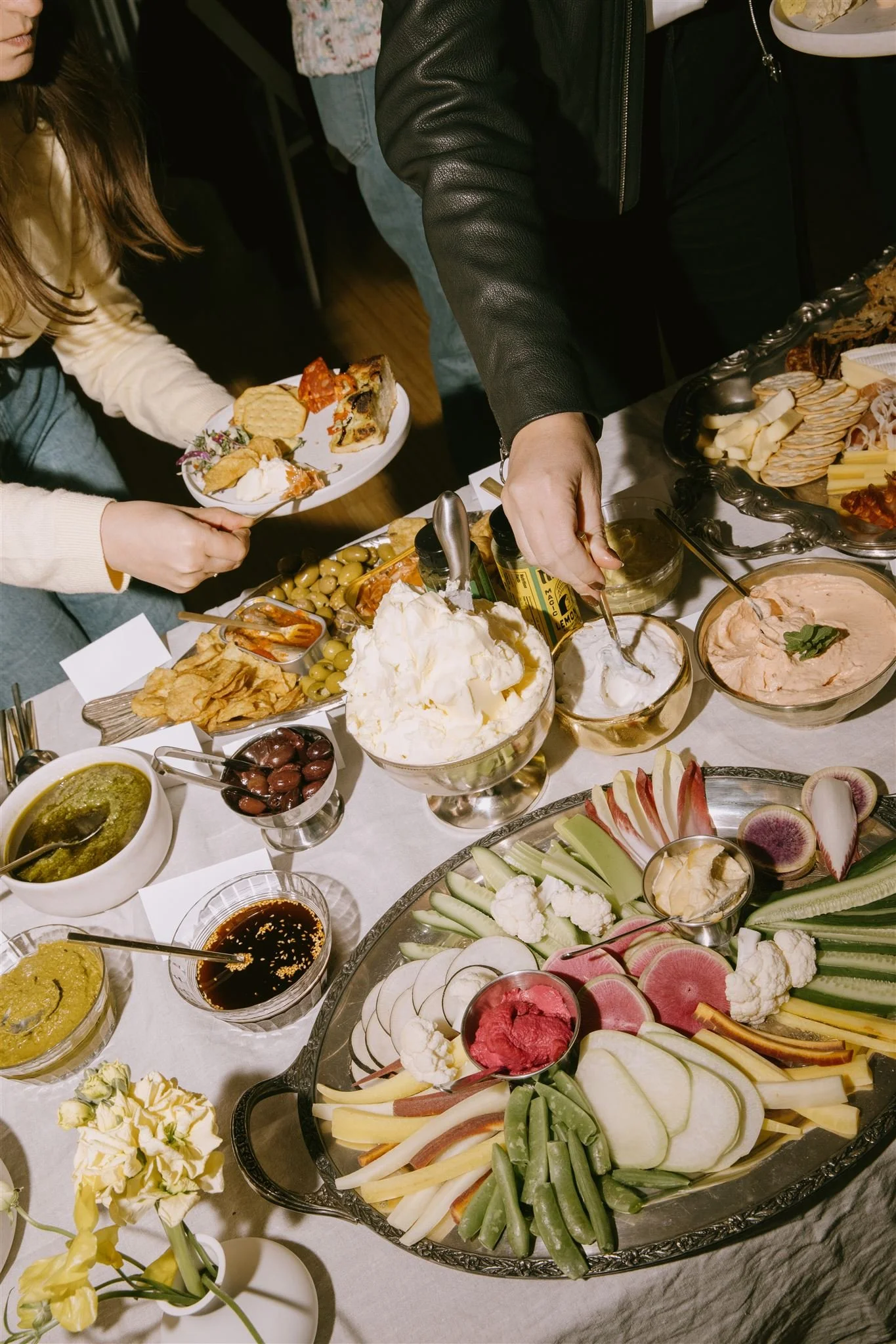 Overhead crudité spread with guests reaching for food at a Bread & Butter Law event