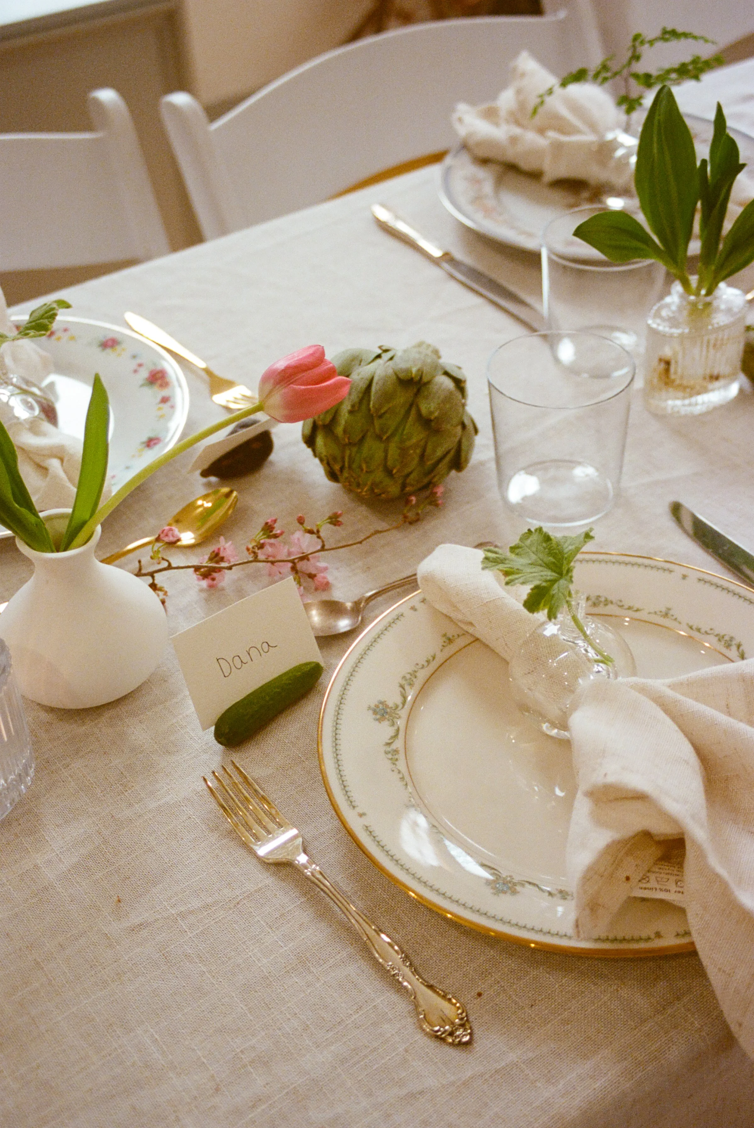 Close-up spring place setting with tulip, artichoke, cherry blossoms and a 'Dana' name card