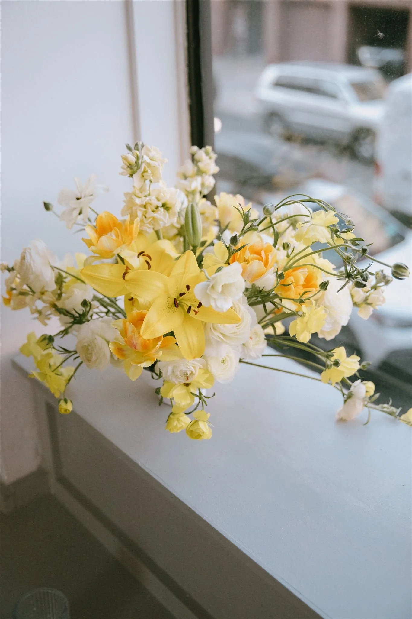 Yellow and white floral arrangement on a windowsill