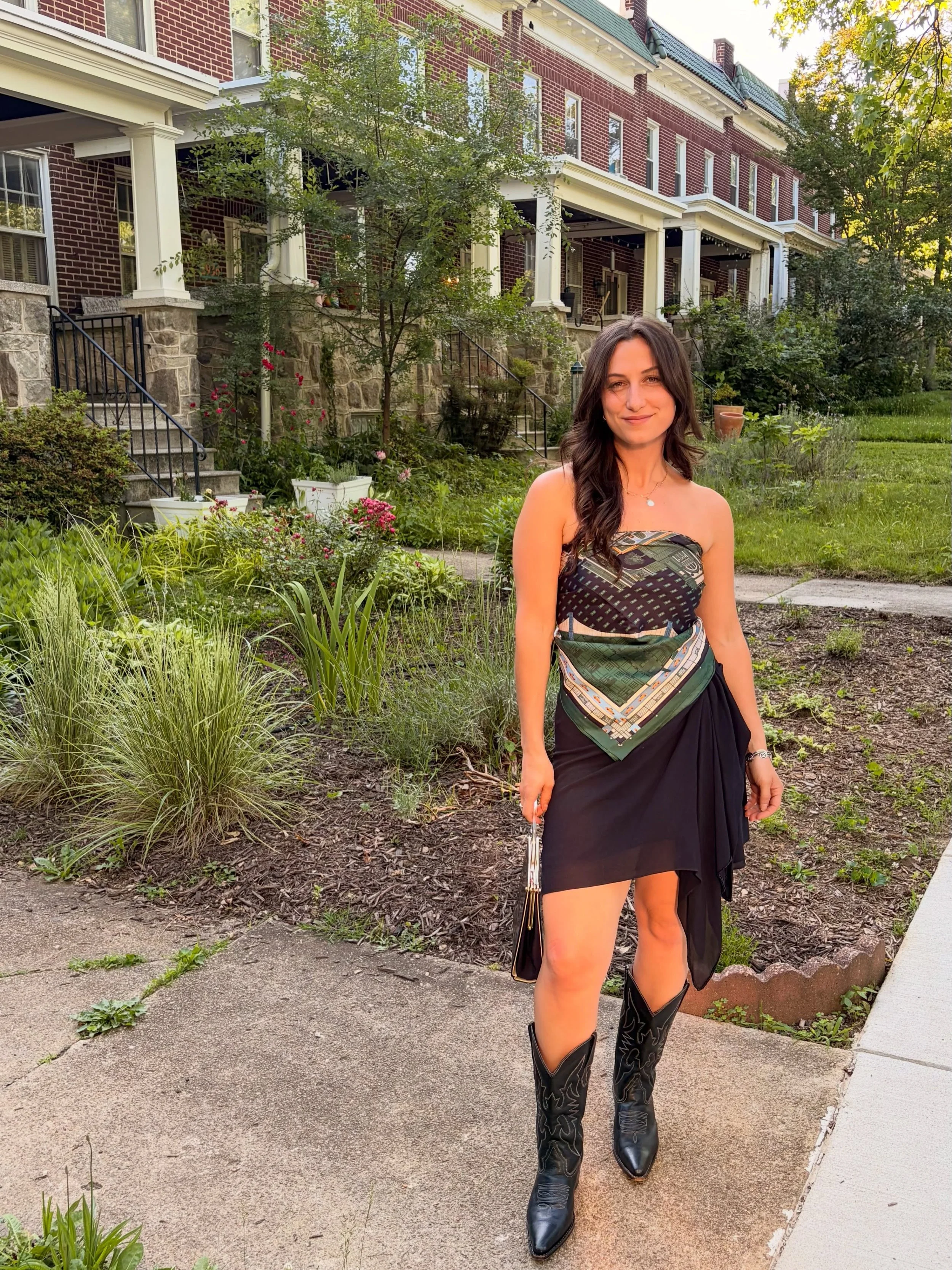 Erica in a bandana top and cowboy boots outside brick rowhouses