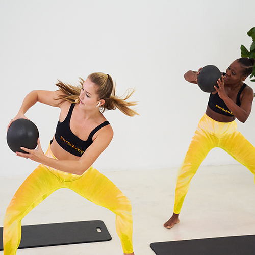 Two women in Physique 57 leggings holding exercise balls