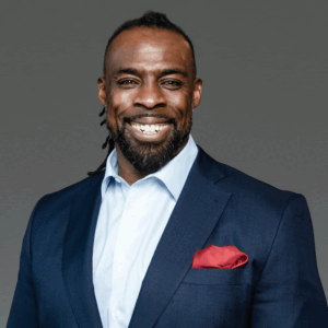 Pierre Campbell, smiling in a navy blazer with a red pocket square