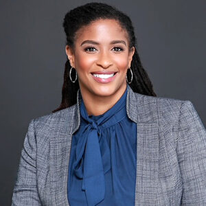 Angel Henry, smiling in a gray blazer and blue blouse