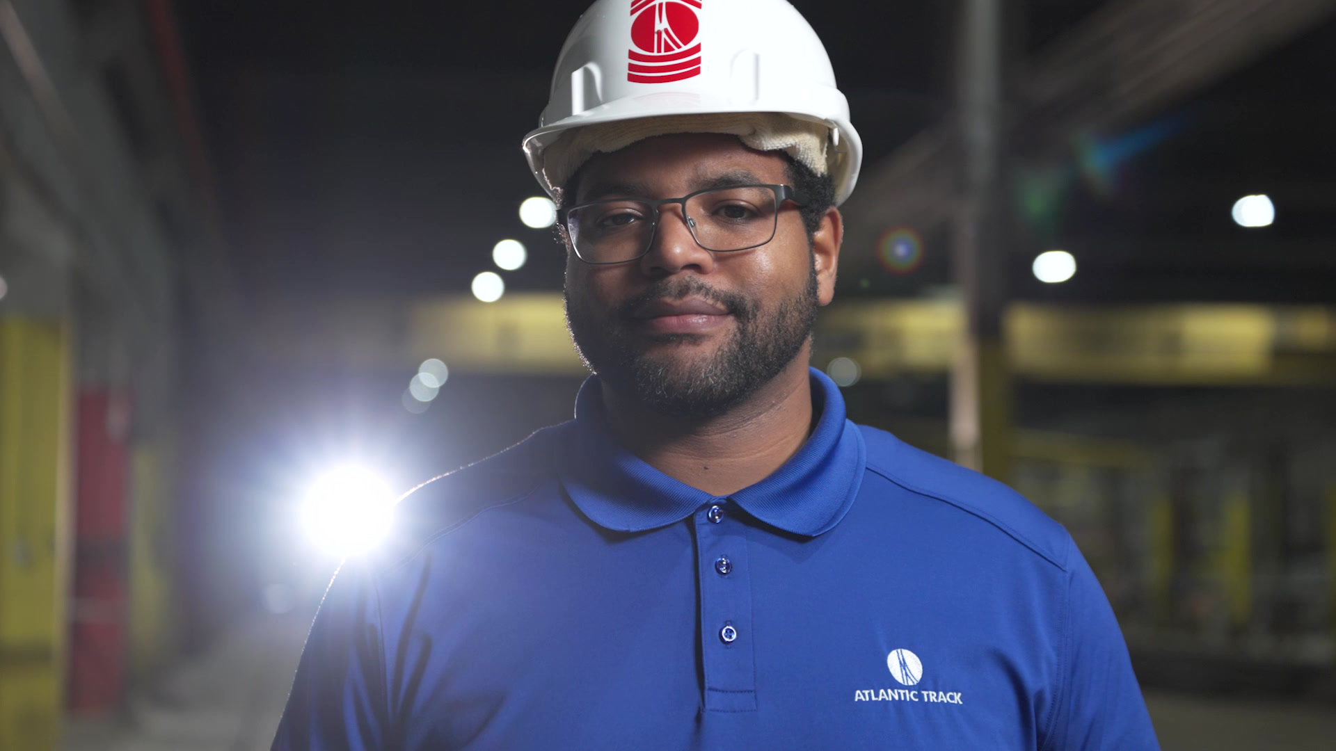 Worker in a hard hat and Atlantic Track branded polo in an industrial facility