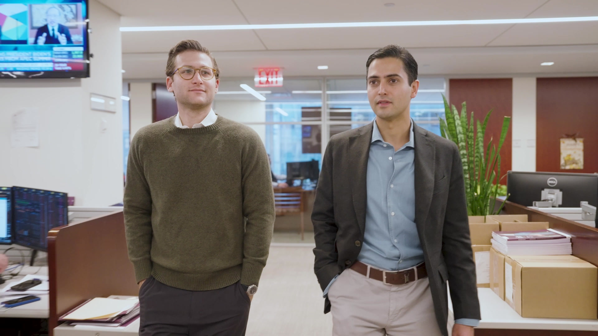 Two men in business casual in an open-plan newsroom — Guggenheim Brand Sizzle still