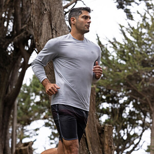 Man in a grey athletic top running along a forest trail