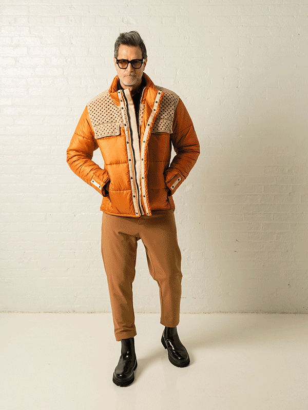 Animated look sequence of a silver-haired model in an orange puffer jacket against a white brick wall