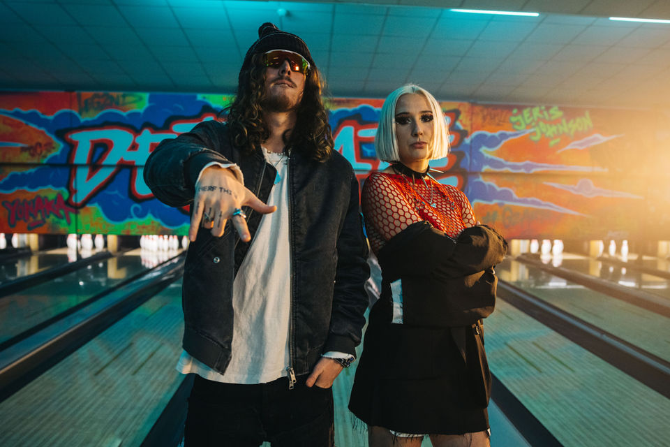 Two musicians posing in a graffiti-covered bowling alley