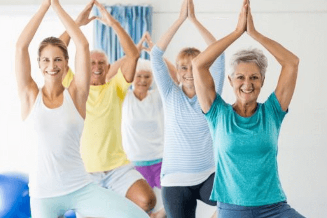 Group of adults doing a tree-pose yoga exercise