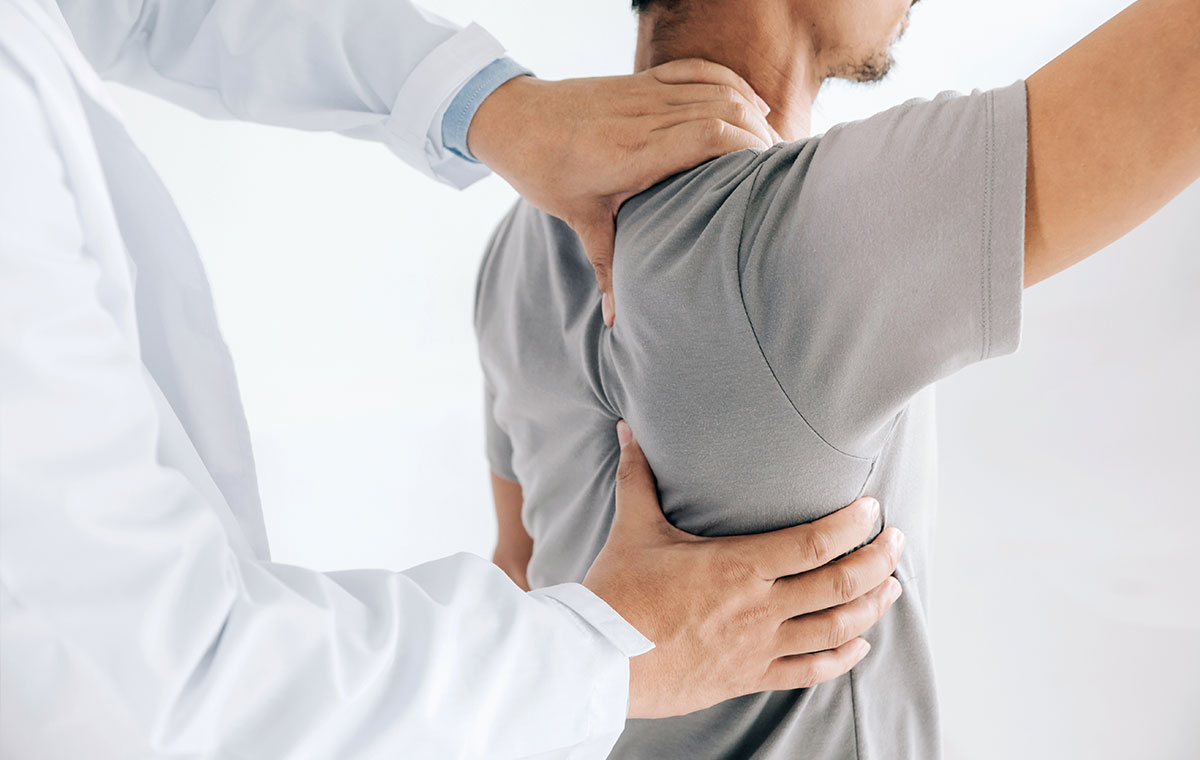 Doctor performing a shoulder and back assessment on a male patient