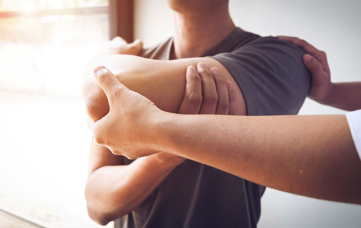 Therapist performing an arm and elbow range-of-motion assessment on a patient