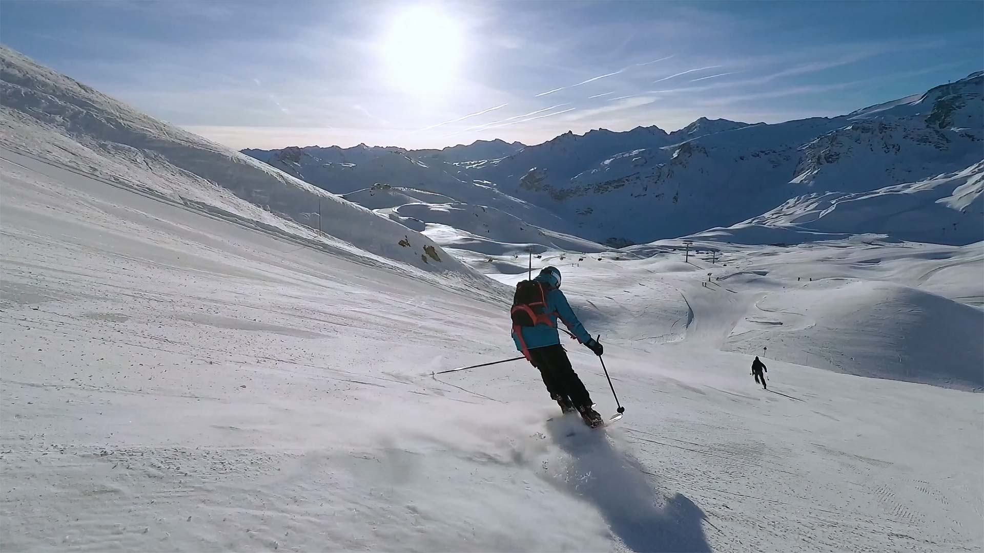 Skier carving down a sunny alpine slope