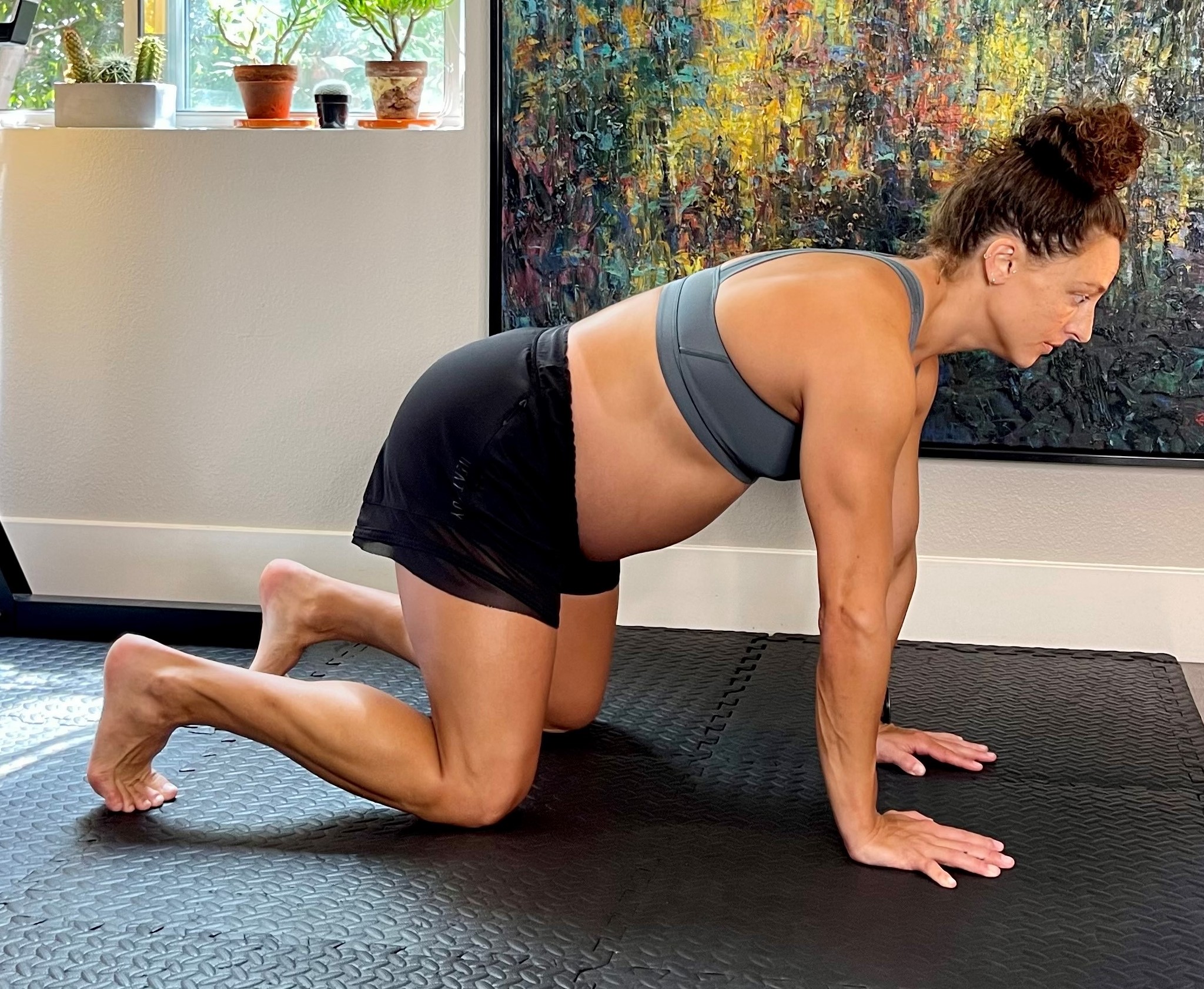 Visibly pregnant woman in a quadruped position on a mat