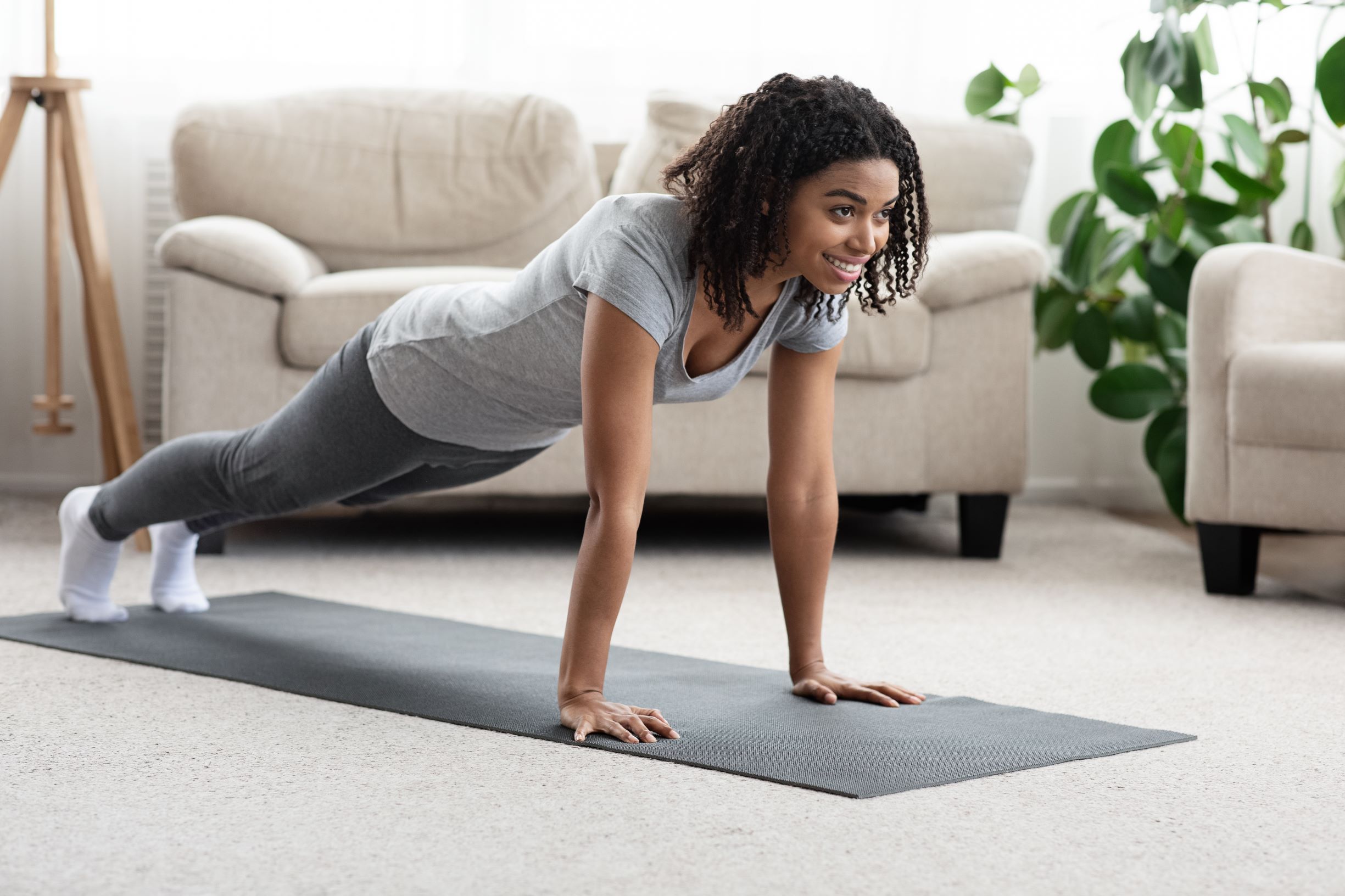 Woman performing a high plank on a mat in her living room