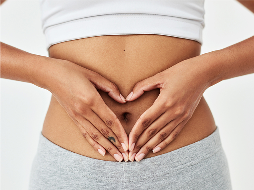 Woman’s midriff with hands forming a heart shape over her navel