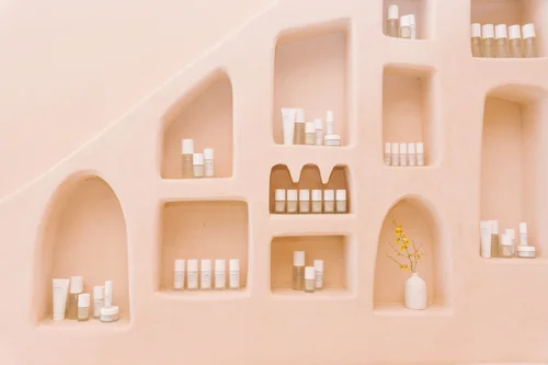 The Outset skincare products displayed on a pink arched shelving wall