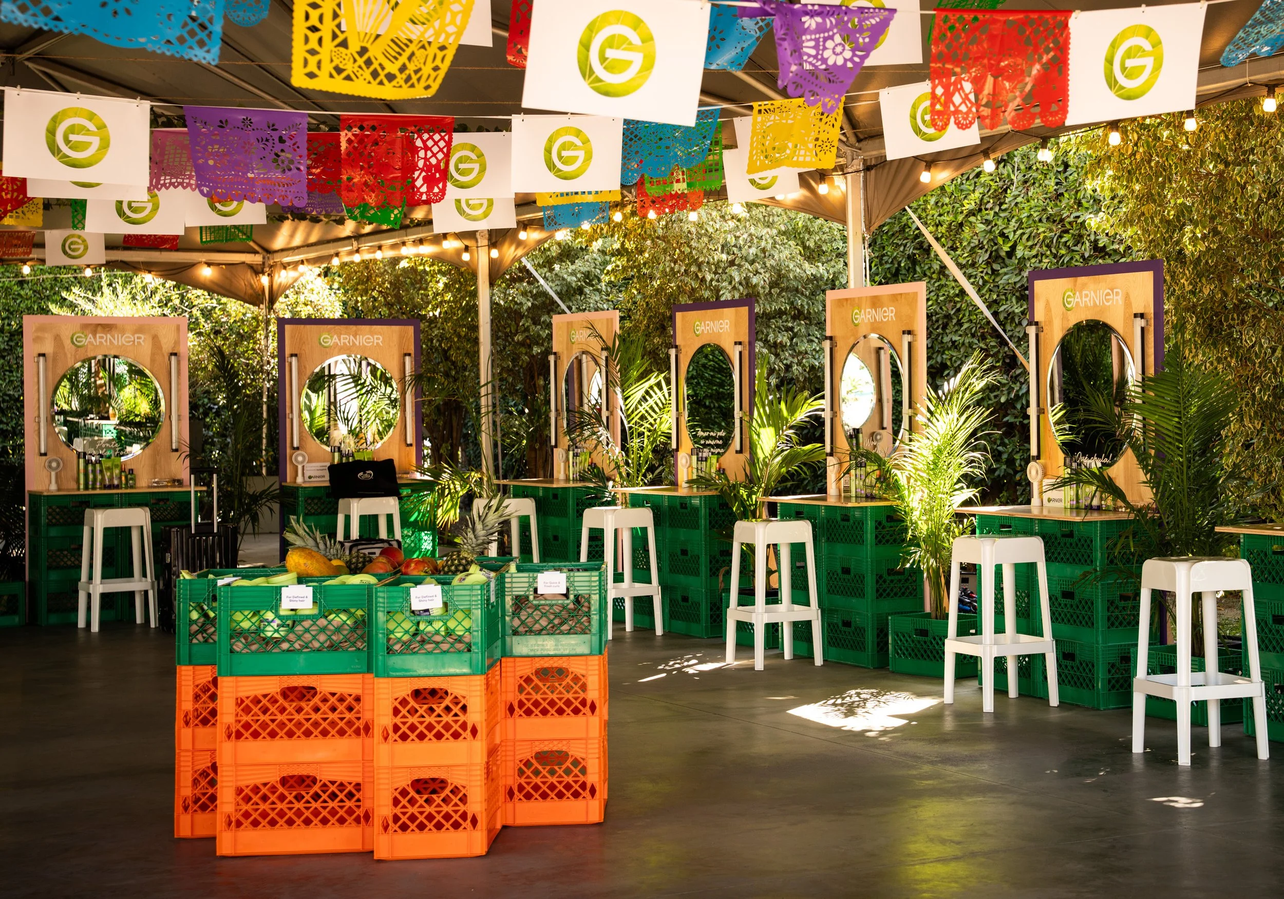 Garnier branded experiential activation space with colorful papel picado banners, green crates and mirrors
