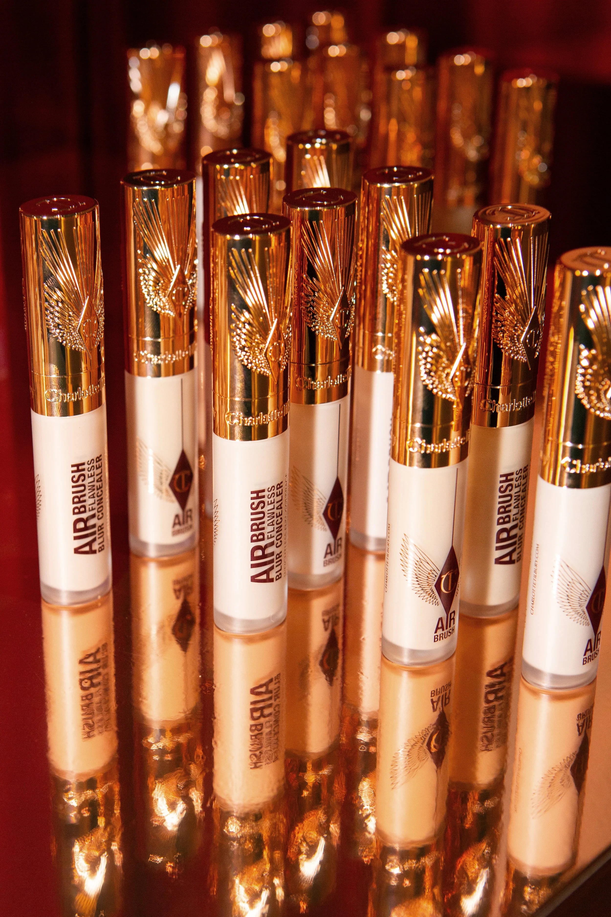 Close-up of Charlotte Tilbury Airbrush Flawless Blur Concealer tubes on a gold reflective surface