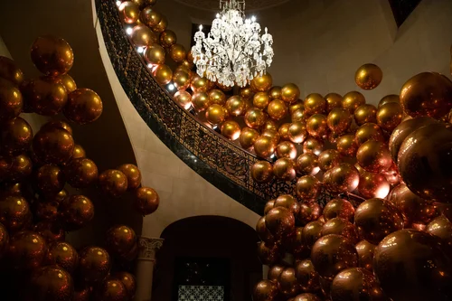 Gold chrome balloon clusters on an ornate staircase