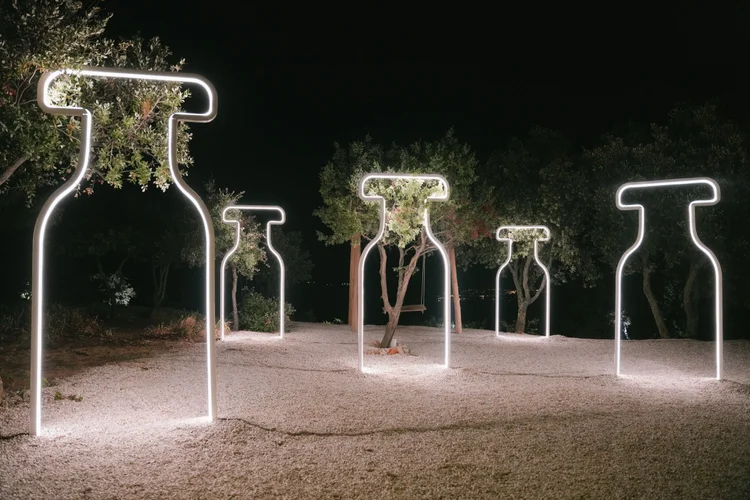Neon bottle-shaped light sculptures outdoors at night