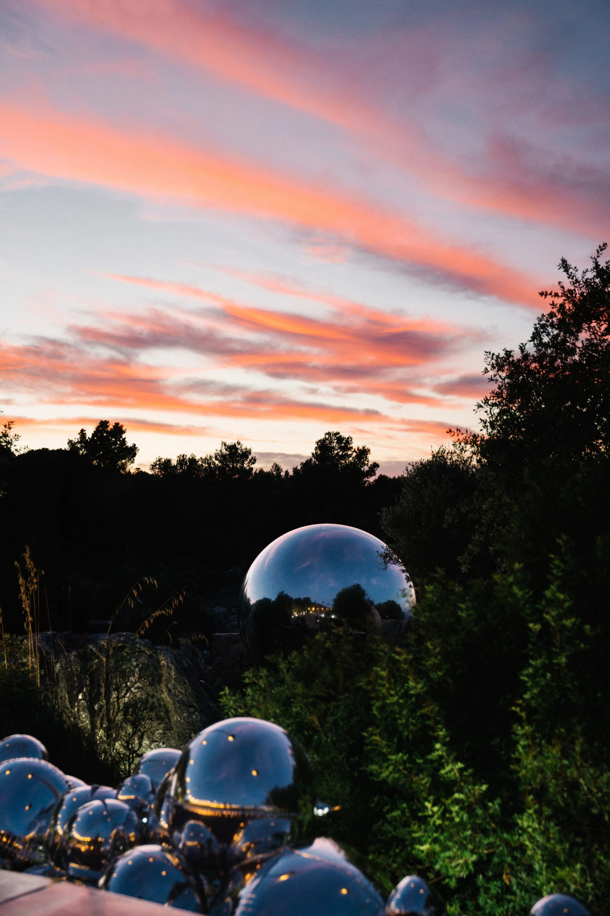 Mirrored chrome spheres among trees at sunset for the Tory Burch Sublime installation