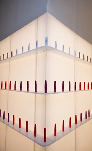 Illuminated corner display shelving lined with rows of colorful lip product sticks