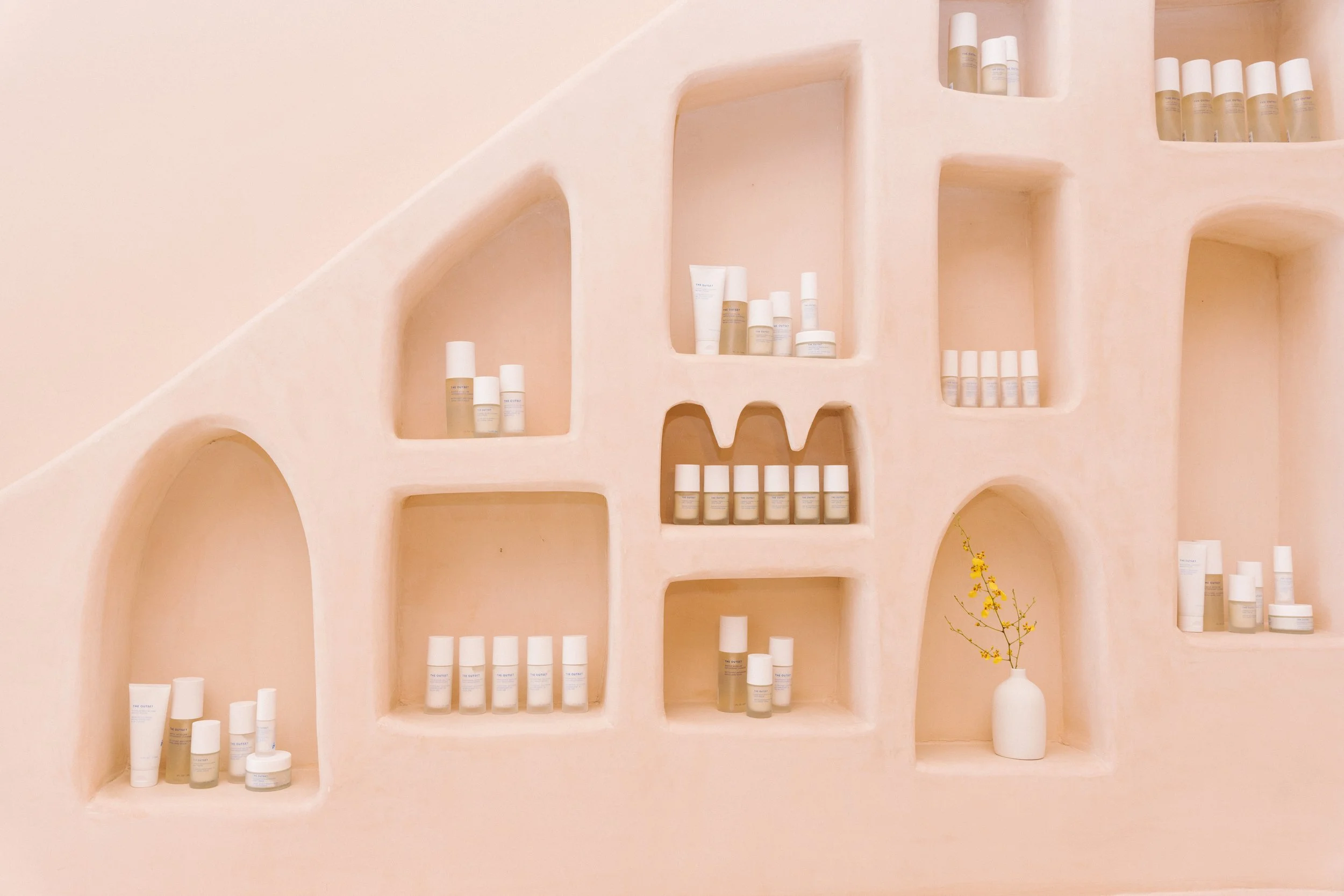 Pink plaster arched shelving wall displaying skincare in a pop-up retail setting